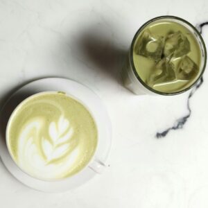 Elegant matcha latte with latte art and iced green tea on a marble table, perfect for tea enthusiasts.