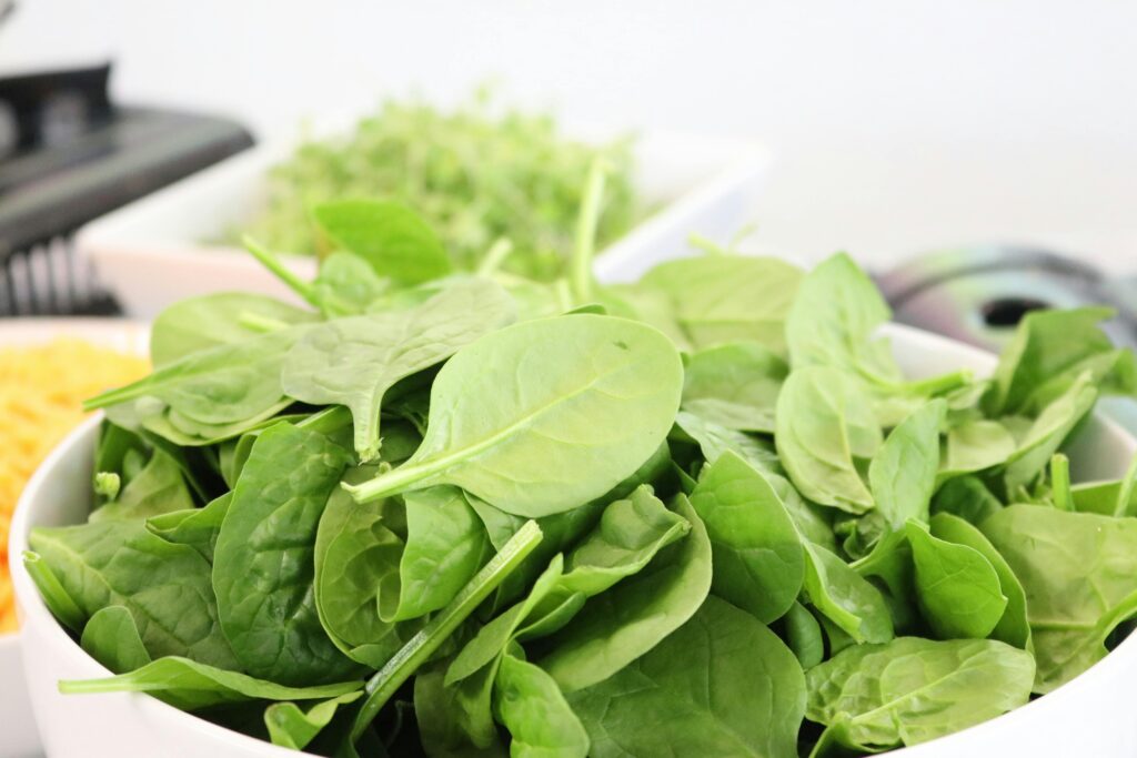 A close-up of fresh spinach leaves in a white bowl, ideal for healthy salads.
